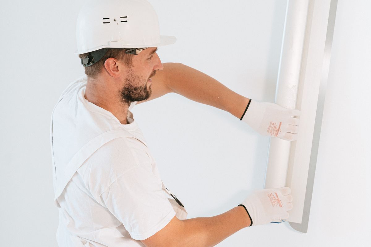 Plâtrier-plaquiste installant un élément de finition intérieure