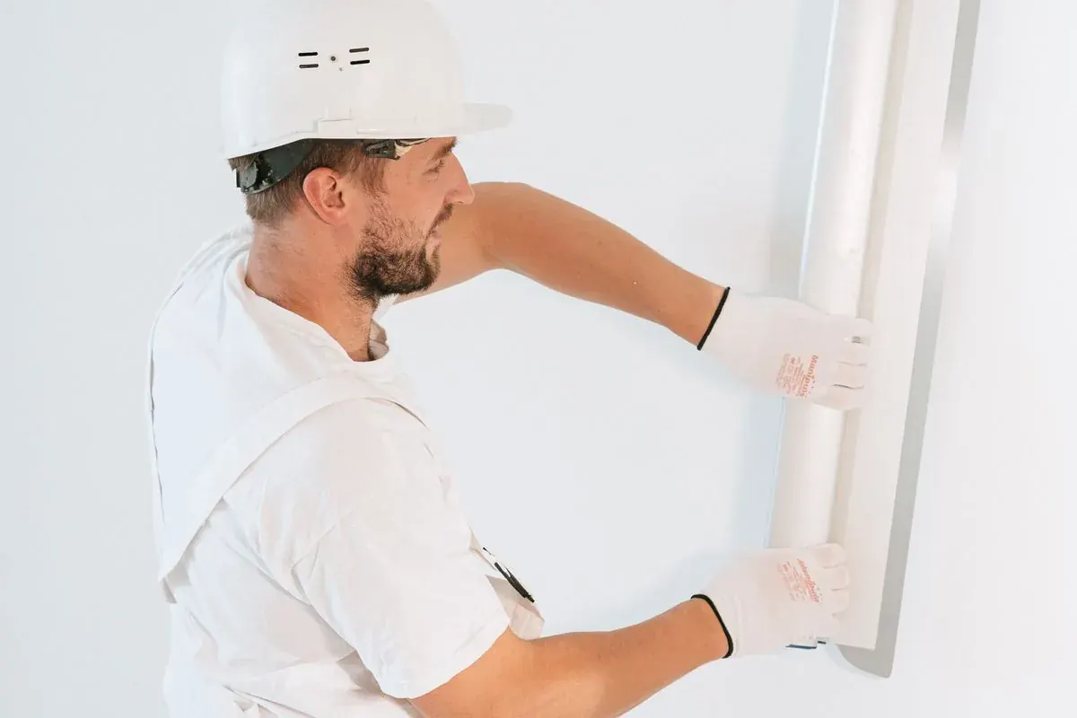 Plâtrier-plaquiste installant un élément de finition intérieure