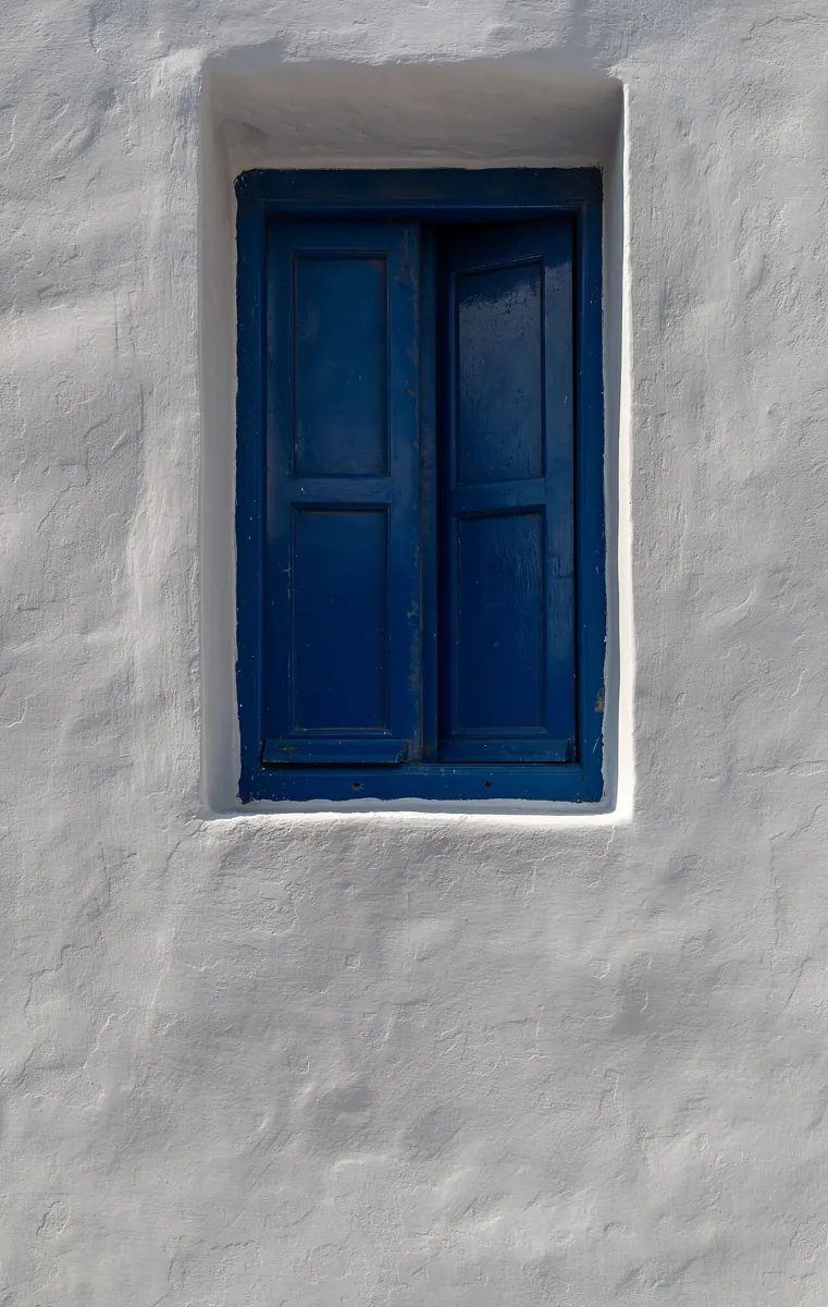 Fenêtre bleue dans un mur enduit clair