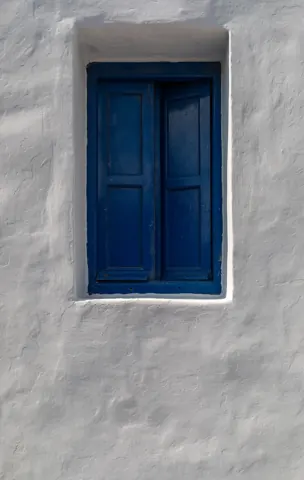 Fenêtre bleue dans un mur enduit clair